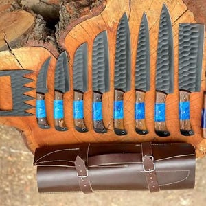 May include: A set of eight black kitchen knives with wooden handles and blue resin accents. The knives are arranged on a wooden surface with a brown leather roll-up case.