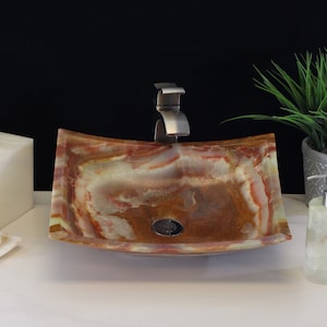 May include: A square, brown, green, and red onyx sink with a silver faucet. The sink is on a white countertop with a white soap dispenser and a white soap dish.