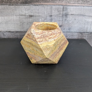 May include: A geometric, multi-faceted planter made of stone with a yellow, brown, and white marbled pattern.