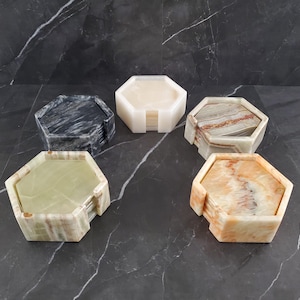 May include: Set of six hexagonal coasters made of natural stone. The coasters are in various colors, including black, white, green, and orange. Each coaster is made of multiple layers of stone, creating a unique pattern.