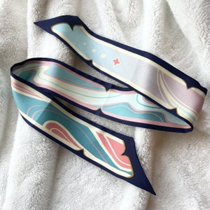 May include: Two silk scarves with a navy blue trim and abstract patterns in shades of pink, blue, and white.