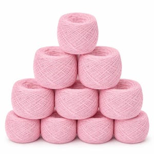 Puede incluir: Una pirámide de diez ovillos de hilo rosa, cada uno con un centro hueco. El hilo es de un color rosa claro y suave, y las bolas están cuidadosamente apiladas sobre un fondo blanco. El hilo parece estar bien enrollado.
