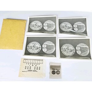 May include: A collection of three black and white photographs featuring Apollo 11 and Gemini 4 mission commemorative buttons, a yellow envelope, a Monkey Color price list card, and a small strip of film negatives showing the same button designs.
