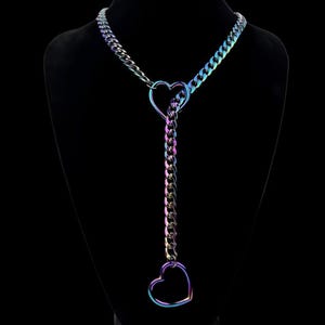 May include: An iridescent rainbow-colored metal chain necklace featuring two heart-shaped links. The chain passes through a heart link at the neckline and terminates in a second heart link at the bottom of the vertical drop section.