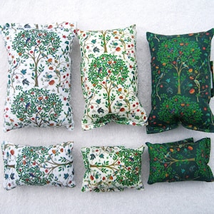 Könnte beinhalten: Sechs Dekokissen mit einem sich wiederholenden Muster aus grünen Bäumen, roten Äpfeln und Vögeln auf weißem Hintergrund. Drei der Kissen haben einen grünen Hintergrund und drei einen weißen Hintergrund.