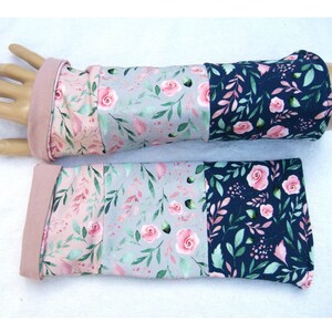Op de afbeelding: Een paar armwarmers met bloemenprint in roze, grijs en marineblauw. De armwarmers zijn gemaakt van een zachte, rekbare stof en hebben een roze manchet.