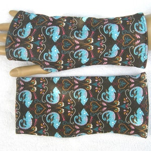 Könnte beinhalten: Ein Paar braune Fingerlose Handschuhe mit einem blauen und rosa Chamäleon-Muster. Die Handschuhe sind aus einem weichen, bequemen Stoff gefertigt und perfekt, um Ihre Hände in den kühleren Monaten warm zu halten.