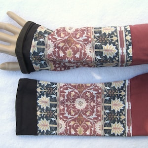 Könnte beinhalten: Ein Paar Armwärmer in Rot und Schwarz mit einem floralen Muster. Die Armwärmer sind aus einem weichen, dehnbaren Stoff gefertigt und perfekt, um die Arme in den kühleren Monaten warm zu halten.