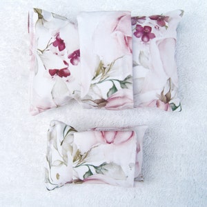 Könnte beinhalten: Drei Kissenbezüge aus Stoff mit Blumendruck, zwei große und ein kleiner, mit weißem Hintergrund und rosa und burgunderfarbenen Blumen.