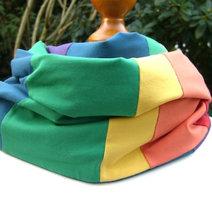 Könnte beinhalten: Ein farbenfroher Infinity-Schal aus Stoff in Blautönen, Grün, Gelb, Orange und Rot. Der Schal ist gefaltet und in einem Regenbogenmuster angeordnet.