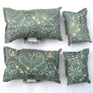 Könnte beinhalten: Vier grüne Zierkissen in verschiedenen Größen mit floralem Muster. Die Kissen haben ein traditionelles Design mit einem sich wiederholenden Muster aus Blumen und Blättern.