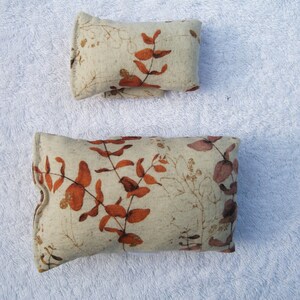May include: Two rectangular cushions with a beige linen fabric and a brown and gold floral print. The cushions are different sizes.