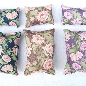 May include: Six decorative cushions with floral patterns. The cushions are in various colours, including pink, green, brown, and black. The floral patterns are all different, but they all have a vintage feel.