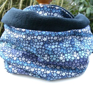 Könnte beinhalten: Ein blauer und weißer, mit Blumen gemusterter Halsschmeichler mit schwarzem Fleece-Futter.