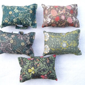 May include: Five rectangular decorative cushions with floral patterns in various colours. The cushions feature designs in shades of green, brown, pink, and yellow. The patterns include flowers, leaves, and other botanical elements, creating a vintage aesthetic.