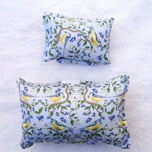 Könnte beinhalten: Zwei blaue und weiße Kissen mit einem Muster aus Vögeln und Blumen. Die Kissen sind rechteckig und haben eine weiche, plüschige Textur.