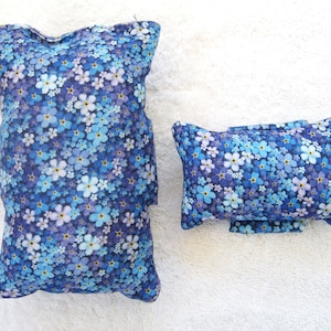 May include: Two blue and white floral patterned pillows. The larger pillow is rectangular and the smaller pillow is a standard pillow shape.