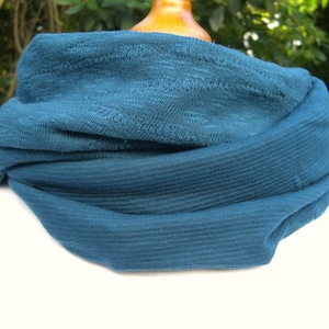 May include: A teal blue knitted neck warmer or scarf. The fabric is soft and textured.
