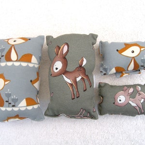 Könnte beinhalten: Vier dekorative Kissen mit Waldmotiv. Zwei Kissen sind grau mit einem braunen Fuchsdesign, ein Kissen ist grün mit einem braunen Hirschdesign und ein Kissen ist grün mit einem braunen Hirschdesign.