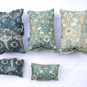 May include: Five decorative cushions with a floral pattern in shades of green, white and brown. The cushions are made of fabric and have a rectangular shape.