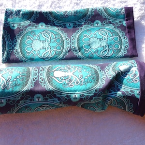 Puede incluir: Calentadores de brazo turquesa y morados con un dise&ntilde;o de pulpo. La tela presenta un patr&oacute;n ovalado con un pulpo en el centro, rodeado de adornos. Los pu&ntilde;os son de color morado liso.