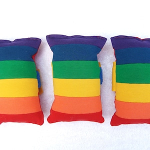 May include: Three rainbow-coloured bean bags with purple, blue, green, yellow, orange and red stripes.