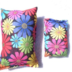 May include: Two decorative cushions with a floral design. The cushions display large, colourful flowers in shades of red, pink, blue, yellow, and green against a dark background. The cushions are rectangular and have a soft, inviting appearance.