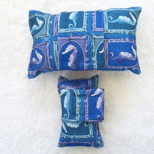 May include: Two blue and purple pillow covers with a seahorse pattern. The larger pillow cover is rectangular and the smaller pillow cover is square.