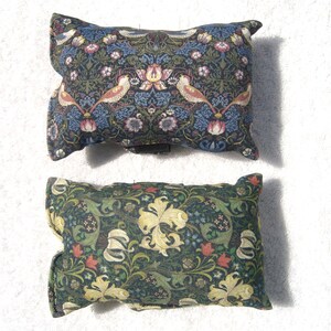 May include: Two decorative cushions featuring a floral and bird design. The cushions are made from a dark green fabric with a light green, yellow and red floral pattern. The cushions have a dark blue border.