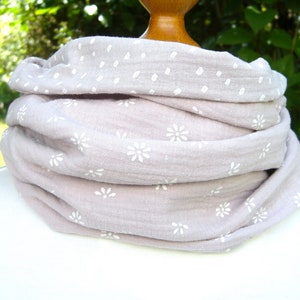 Könnte beinhalten: Ein weicher, hellrosa Schal mit einem weißen Blumenmuster. Der Schal ist gefaltet und auf einer Puppe ausgestellt.