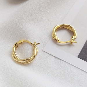May include: A pair of gold-toned hoop earrings with a twisted design. The earrings are small and delicate.