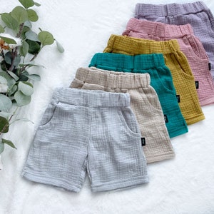 Può includere: Un set di sei paia di pantaloncini in garza di cotone in vari colori, tra cui grigio chiaro, beige, verde, giallo, rosa e viola. I pantaloncini hanno una vestibilità rilassata e sono perfetti per l'estate.