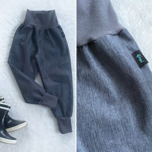 Op de afbeelding: Grijze sweatpants met een brede elastische tailleband en getailleerde pijpen. De sweatpants hebben een klein grijs label met het woord "kiwi" op het rechterbeen.