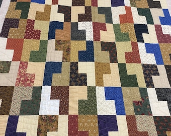 May include: A patchwork quilt with a geometric pattern of squares and rectangles in various shades of brown, green, red, blue, and white.