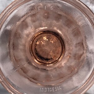 May include: The bottom of a pink glass bowl with the words "C.I.C." and "INDONESIA" etched into the glass.
