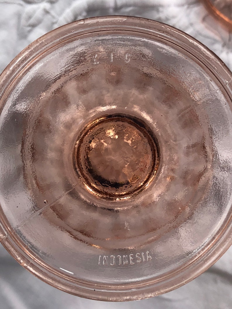 May include: The bottom of a pink glass bowl with the words "C.I.C." and "INDONESIA" etched into the glass.