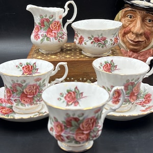 May include: A vintage tea set with a floral pattern. The cups and saucers are white with a pink and green floral design. There is also a creamer and sugar bowl with the same floral design.