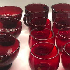 May include: Set of red glass cups and bowls. The set includes a jug, six small cups, and three bowls.