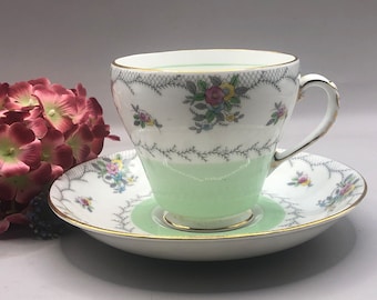 May include: A vintage teacup and saucer set with a delicate floral pattern and a light green base. The cup and saucer have a gold trim and a lace-like design.