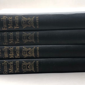 Puede incluir: Cuatro libros encuadernados en tapa dura de color negro apilados uno encima del otro. Los libros se titulan "The Family Mark Twain" y tienen un emblema dorado en el lomo. Los libros son publicados por Harper.