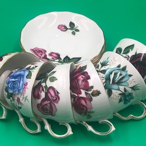 May include: A set of six vintage teacups and saucers with floral designs. The cups and saucers feature a white background with pink, blue, and green floral patterns.
