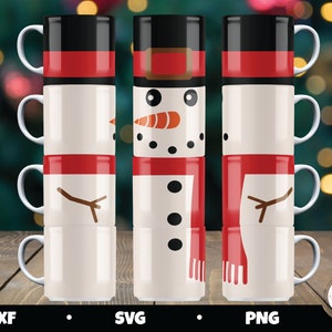 Op de afbeelding: Set van drie witte keramische mokken met sneeuwmanontwerpen. De mokken zijn op elkaar gestapeld. De bovenste mok heeft een zwarte hoed, een rode sjaal en een wortelneus. De middelste mok heeft een rode sjaal en een tak voor armen. De onderste mok heeft een rode sjaal en een tak voor armen.