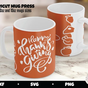 May include: Two orange mugs with white handles. One mug has the text "Happy Thanks Giving" in white lettering. The other mug has a white design of a turkey, a pie, and a pumpkin.