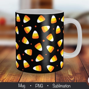 May include: A white ceramic mug with a black background and a pattern of orange and yellow candy corn. The mug has a white handle.