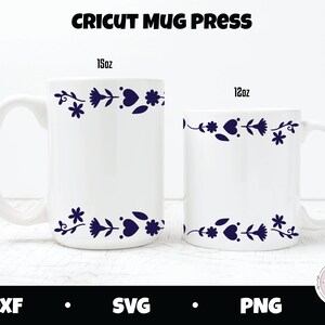 May include: Two white ceramic mugs with a blue floral design around the top rim. The mug on the left is a 15oz mug and the mug on the right is a 12oz mug. The mugs are on a white wood surface.