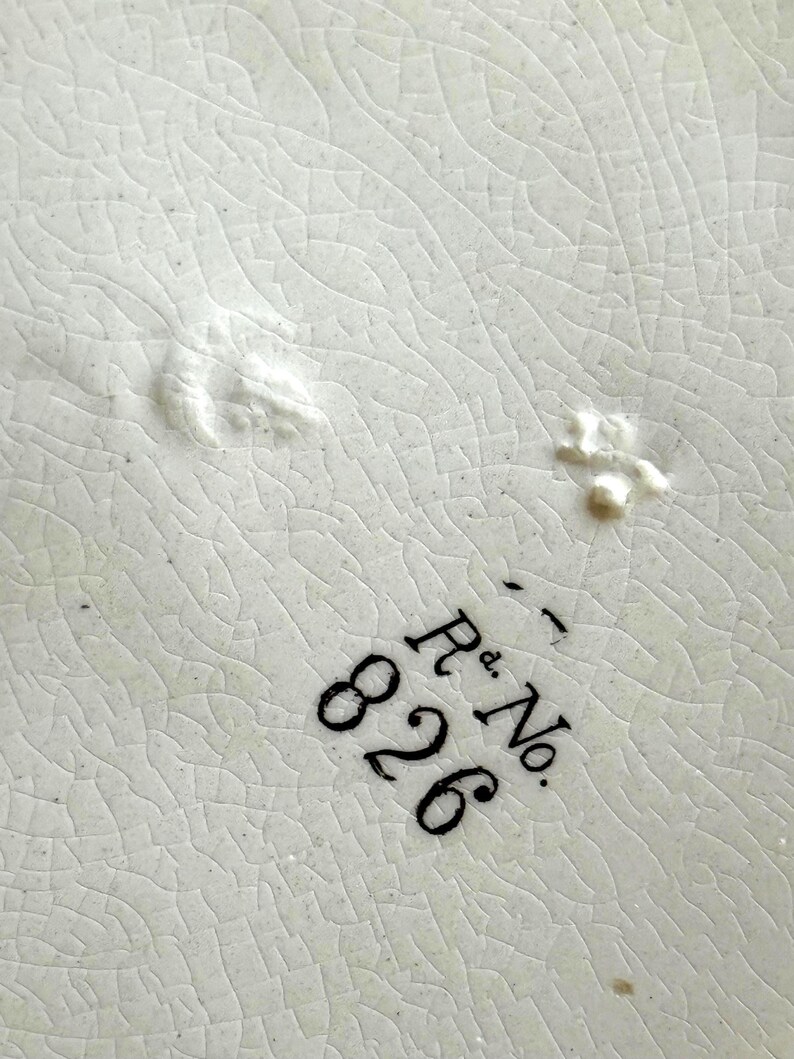 May include: Close-up of a white ceramic surface with a cracked, textured pattern. The image features the black text "R.d. No. 826" in a serif font, indicating a registered design number.