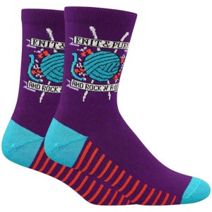 May include: A pair of purple socks with teal toe and heel sections. The socks display a teal yarn ball graphic with the text "KNIT & PURR" and "AND ROCK 'N' ROLL" in white.