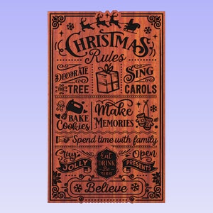May include: A wooden sign with a Christmas theme. The sign has a red background with black text and illustrations. The text reads "Christmas Rules" and includes a list of Christmas activities such as "Decorate the Tree", "Sing Carols", "Bake Cookies", "Make Memories", "Spend time with family", "Stay Jolly", "Eat Drink Be Merry", "Open Presents", and "Believe".