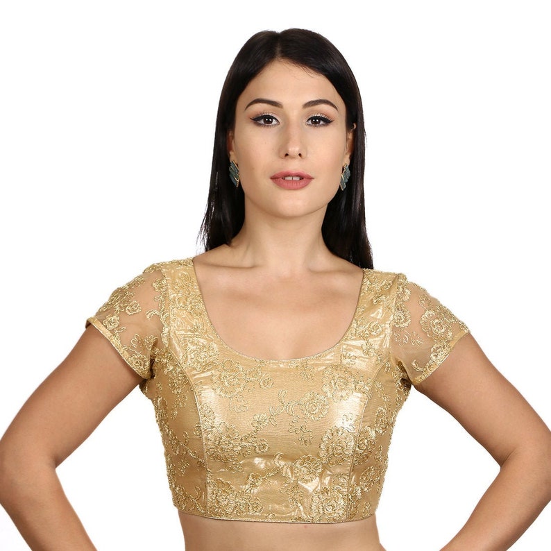 May include: A gold embroidered blouse with a scoop neck and short sleeves. The blouse has a sheer lace overlay and is decorated with floral patterns.