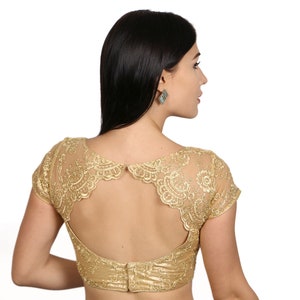 May include: A gold embroidered blouse with a low back and short sleeves. The blouse is made of a sheer fabric with a delicate lace trim.